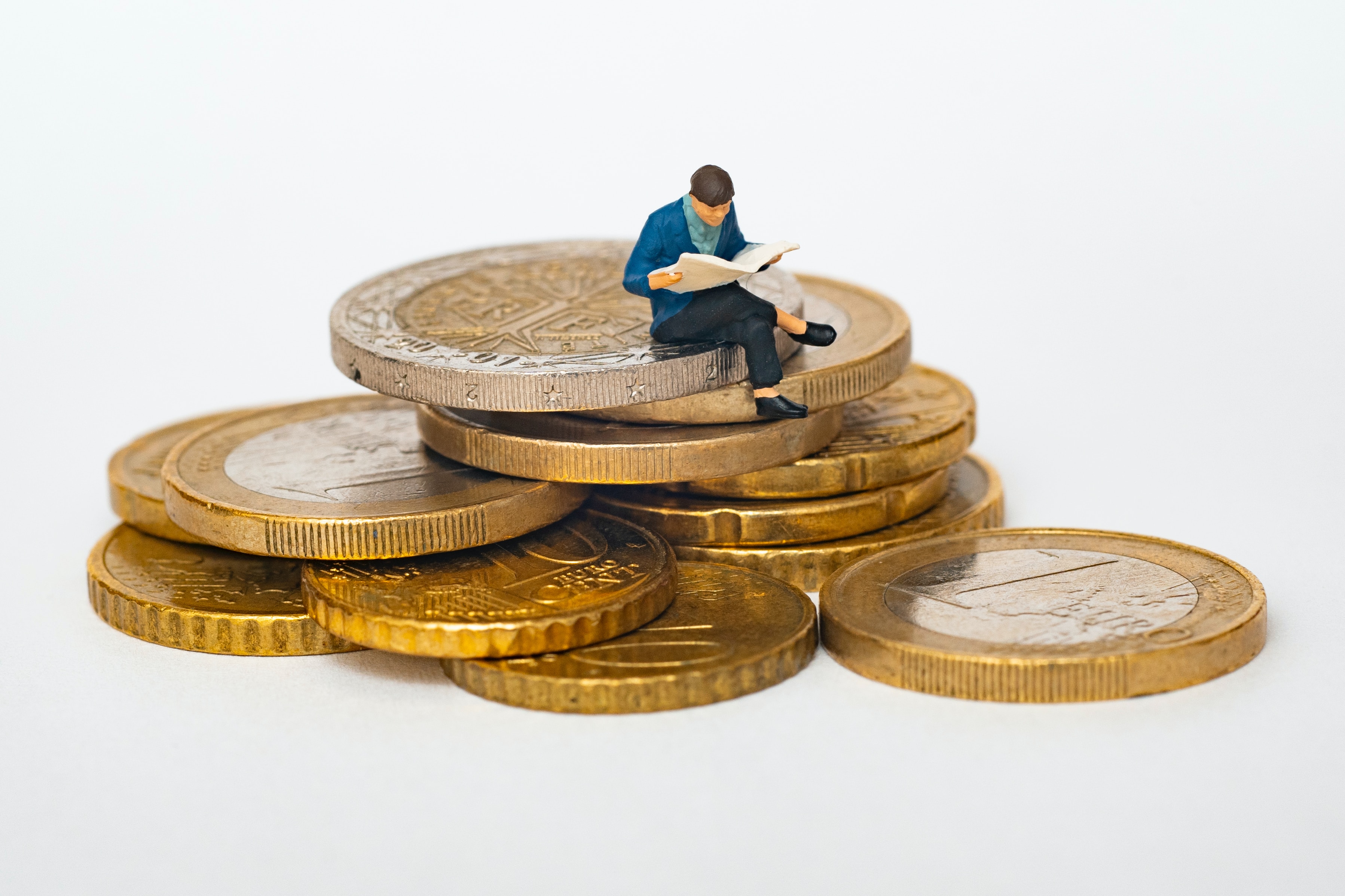 male reading a book sitting on top of gold coins